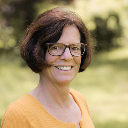 Mitarbeiterfoto vor grünem Hintergrund draußen